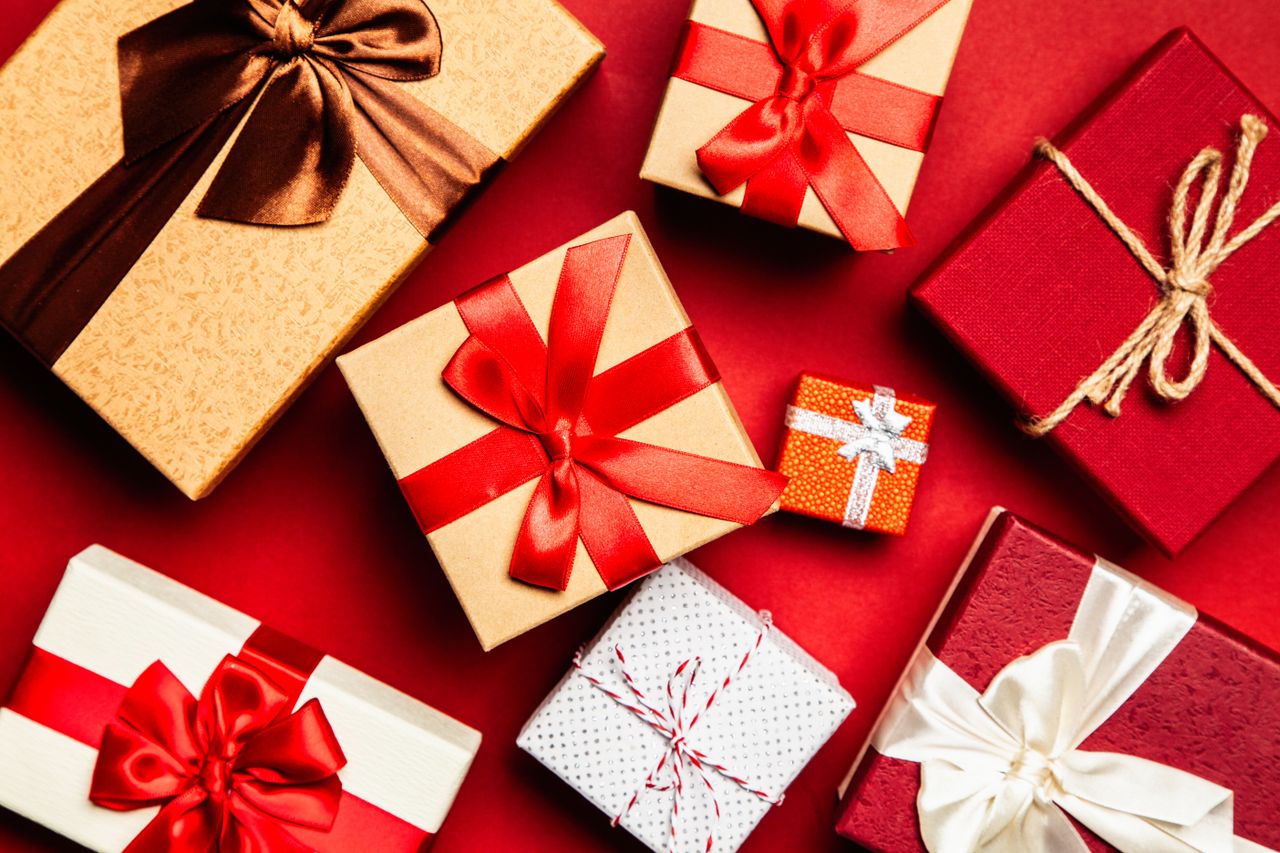 services-01 Top view of beautifully wrapped holiday gifts with red and brown ribbons on a vibrant red background.