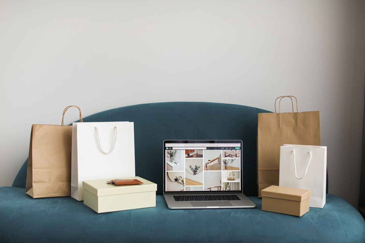 role-01 A laptop surrounded by shopping bags and boxes on a blue sofa, ideal for online shopping themes.