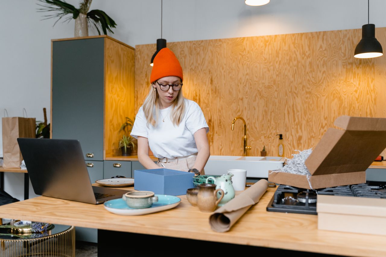 Crafting Captivating Headlines: Your awesome post title goes here Young woman packaging handmade ceramics in a modern kitchen for her online business. Warm interior setting.